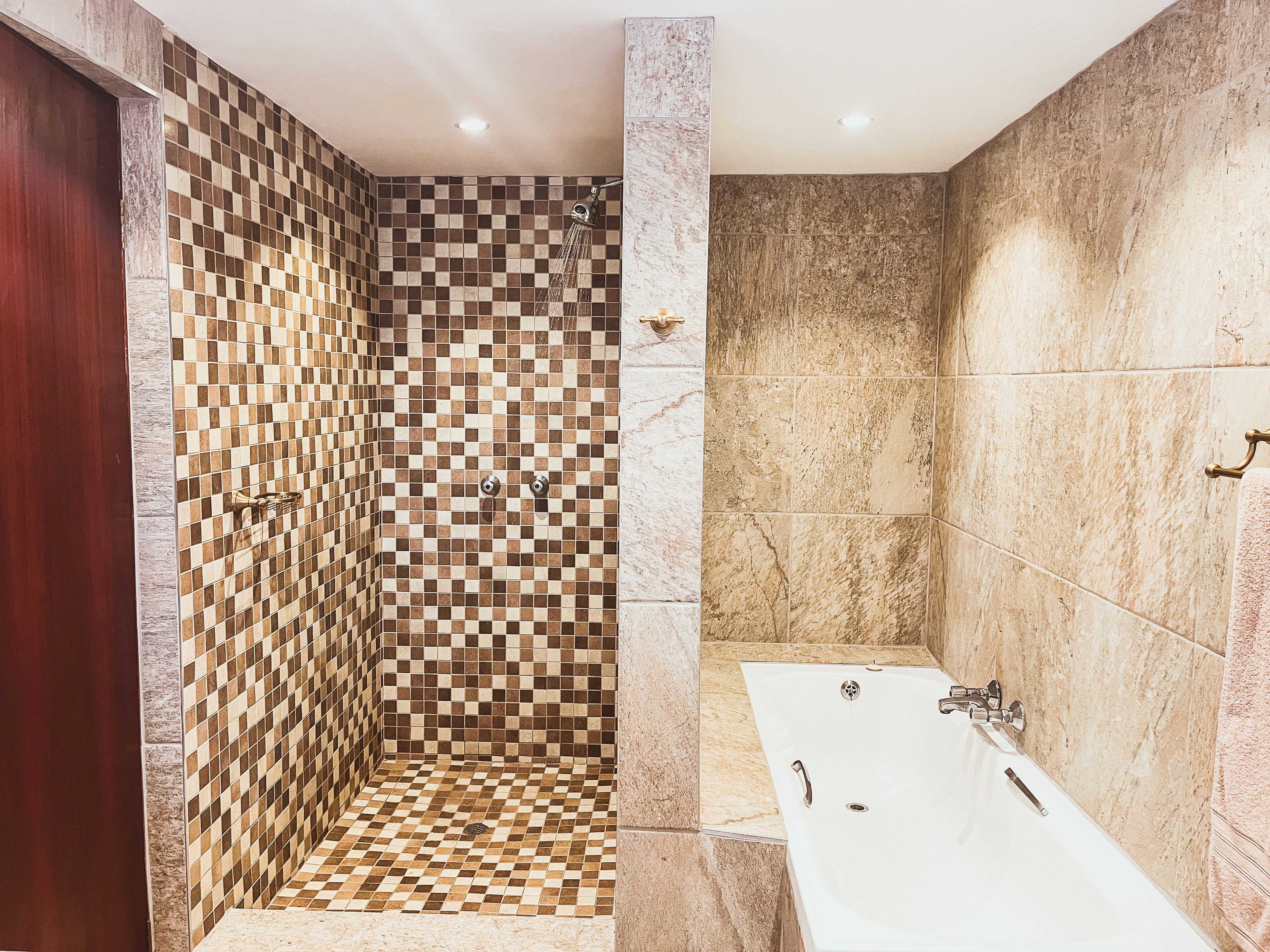 Un baño con pared de ducha a cuadros, bañera y suelo de mármol.