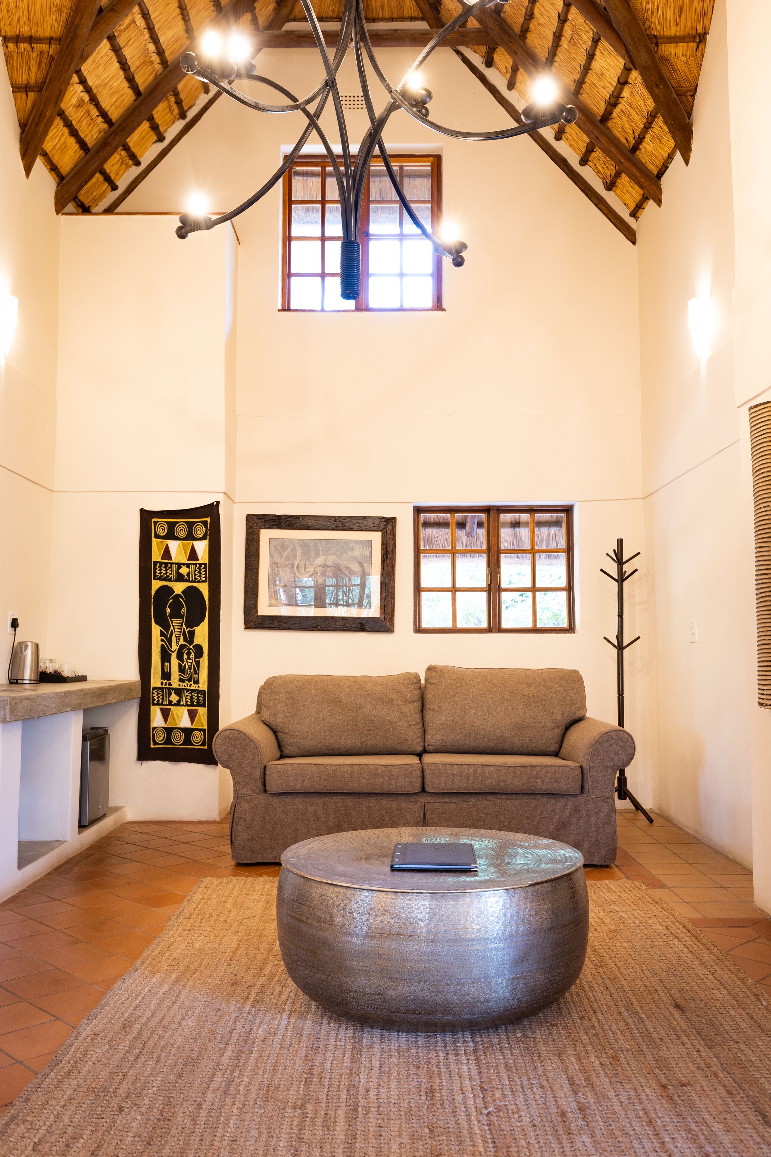A cozy living room with a brown sofa, a round coffee table, and a hanging light fixture.