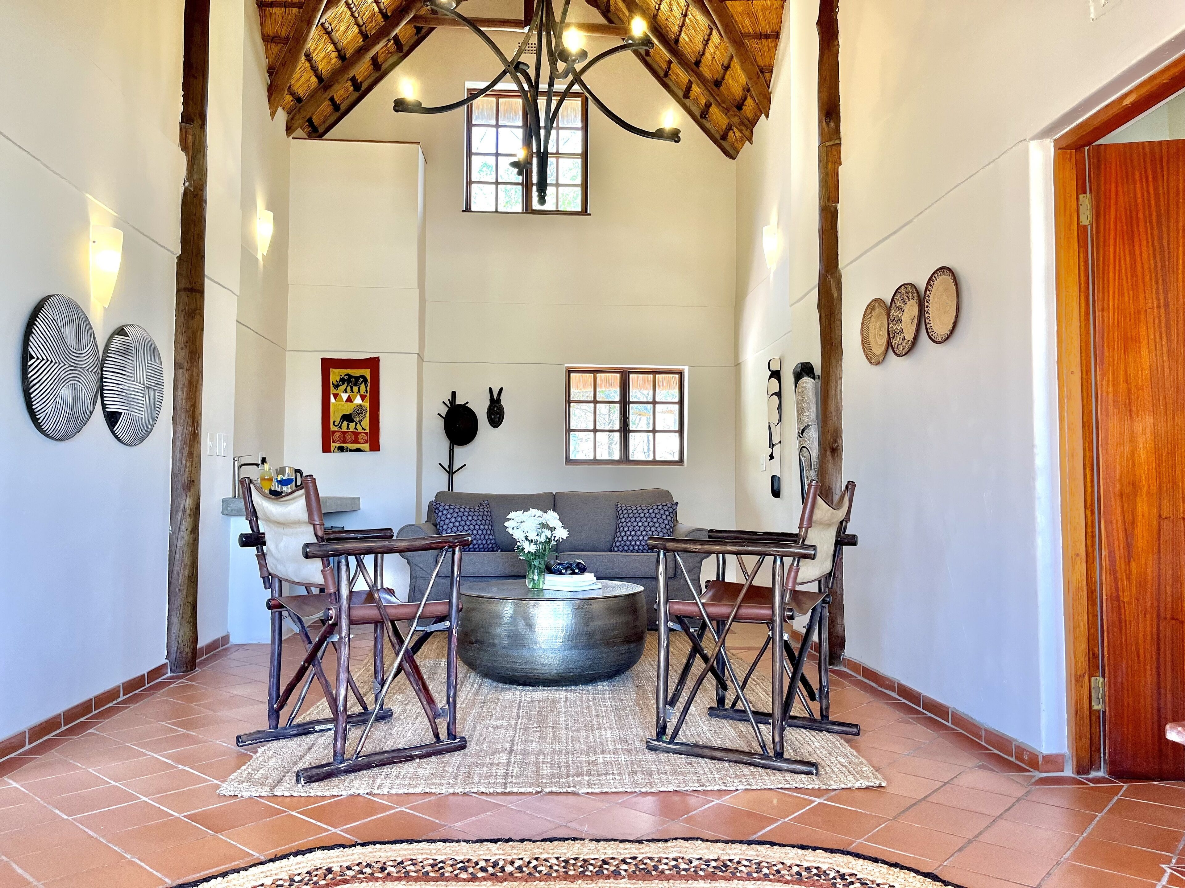 A spacious living area with a high ceiling, a chandelier, and a large round table surrounded by chairs.