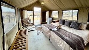A tented accommodation room with a bed, a chair, a desk, and a view of the outdoors. - MILIMA Big 5 Safari Lodge (Hoedspruit)