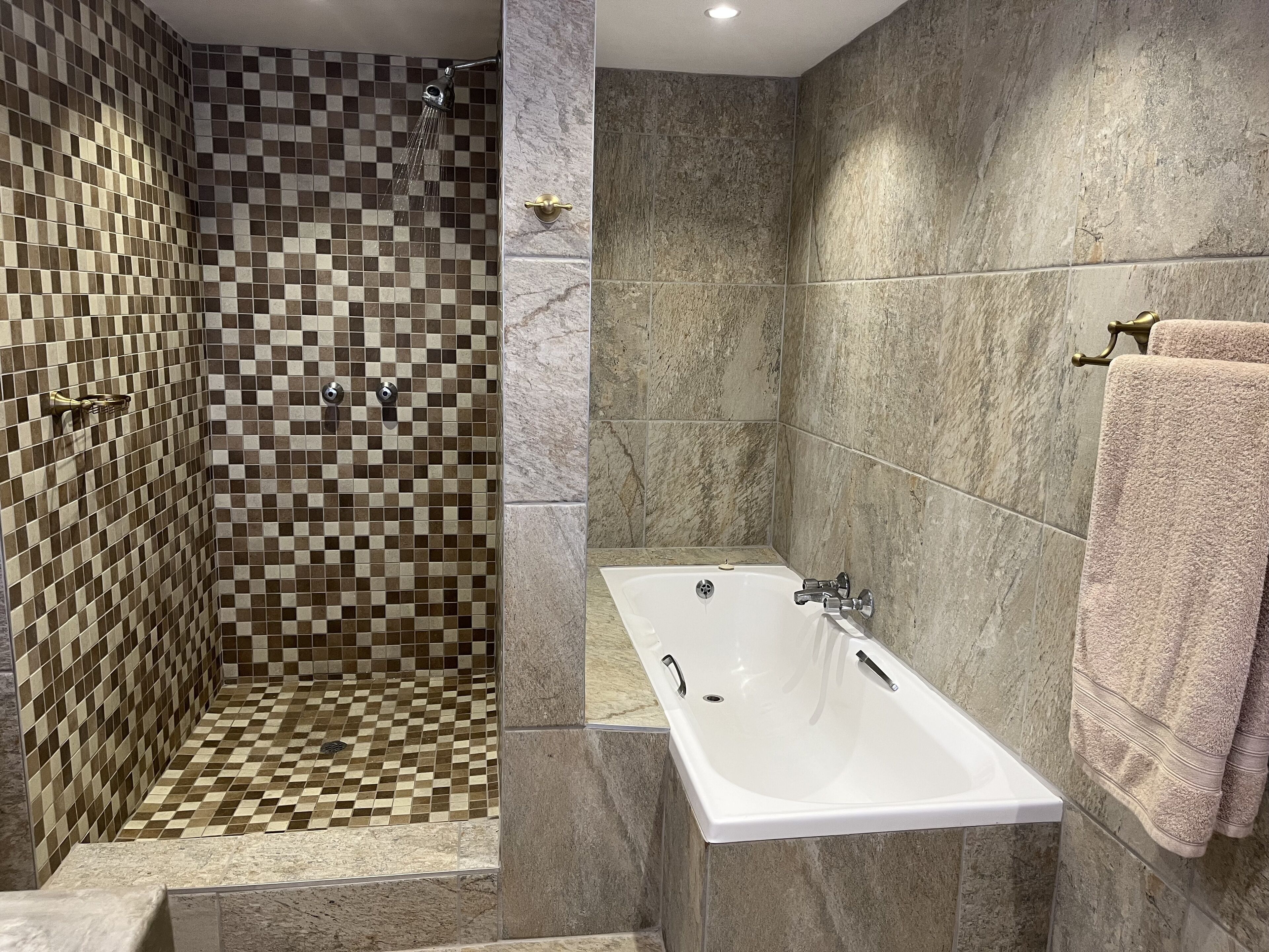 Un baño con pared de ducha a cuadros, una bañera blanca y un perchero para toallas.