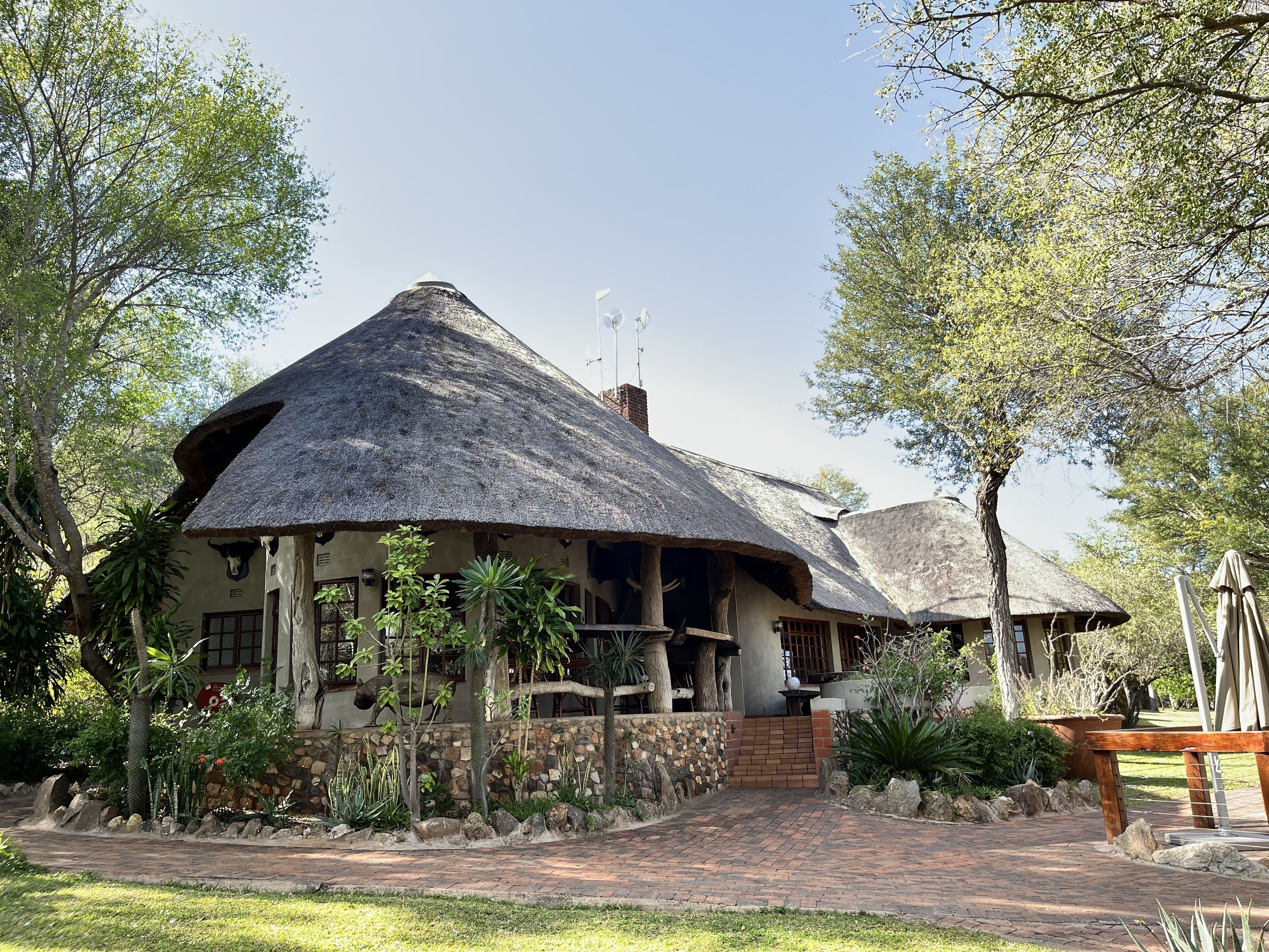 A thatched-roof building with a stone wall and a paved entrance.