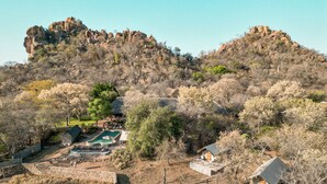 Un paisaje montañoso con zona de piscina, muros de piedra y vegetación escasa.