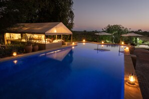 Ein Pool mit überdachter Sitzgelegenheit und Außenbeleuchtung.