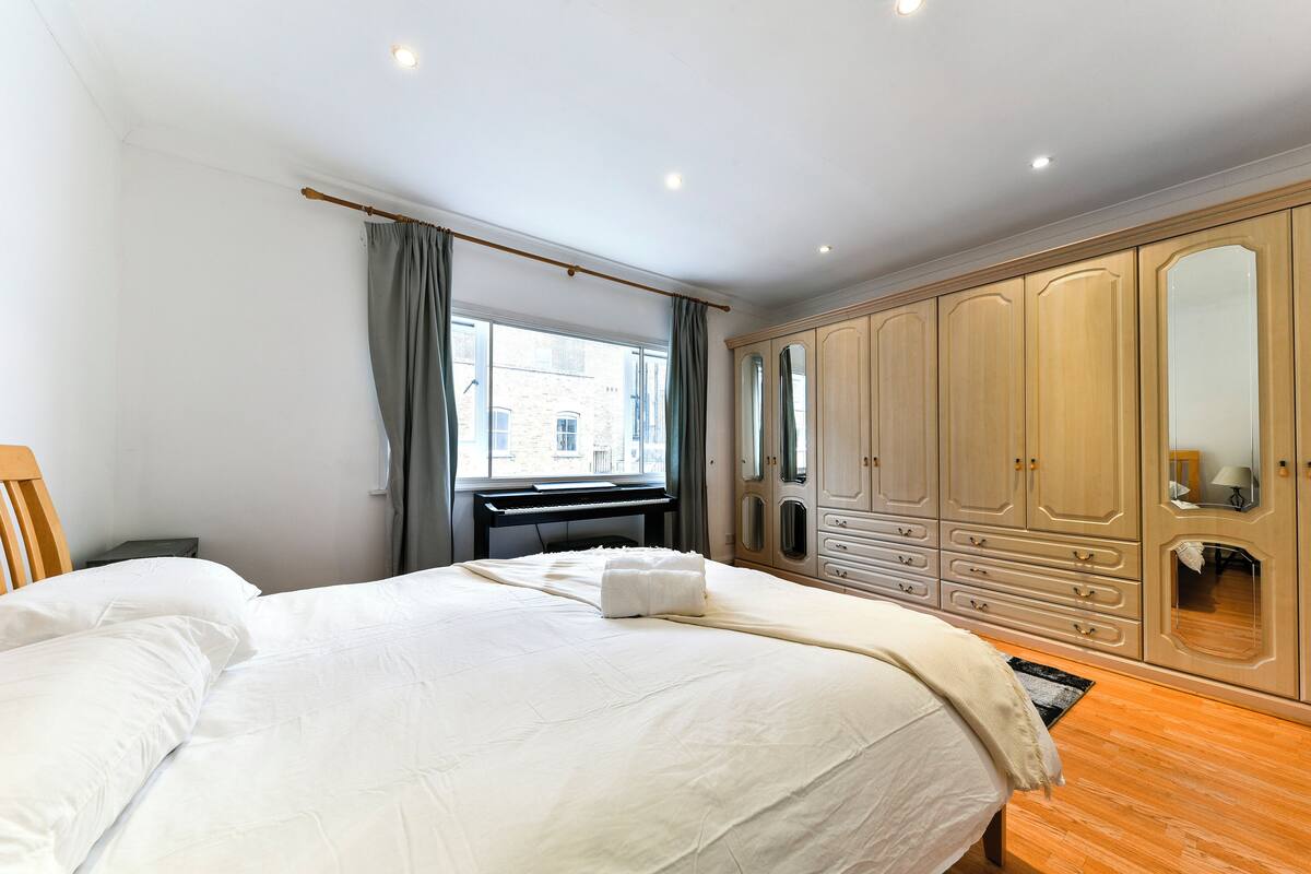 A bedroom with a large bed, a desk, and a wardrobe.