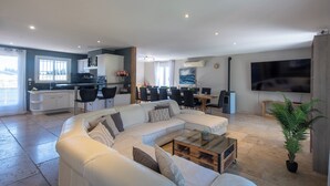A modern living room with a sectional sofa, a coffee table, and a dining area with chairs and a table. - VILLA L'ESTEL in the countryside with private pool 10 minutes from Arles (Tarascon)