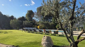 A well-maintained lawn with a large rock, a pool, and lounge chairs. - VILLA L'ESTEL in the countryside with private pool 10 minutes from Arles (Tarascon)