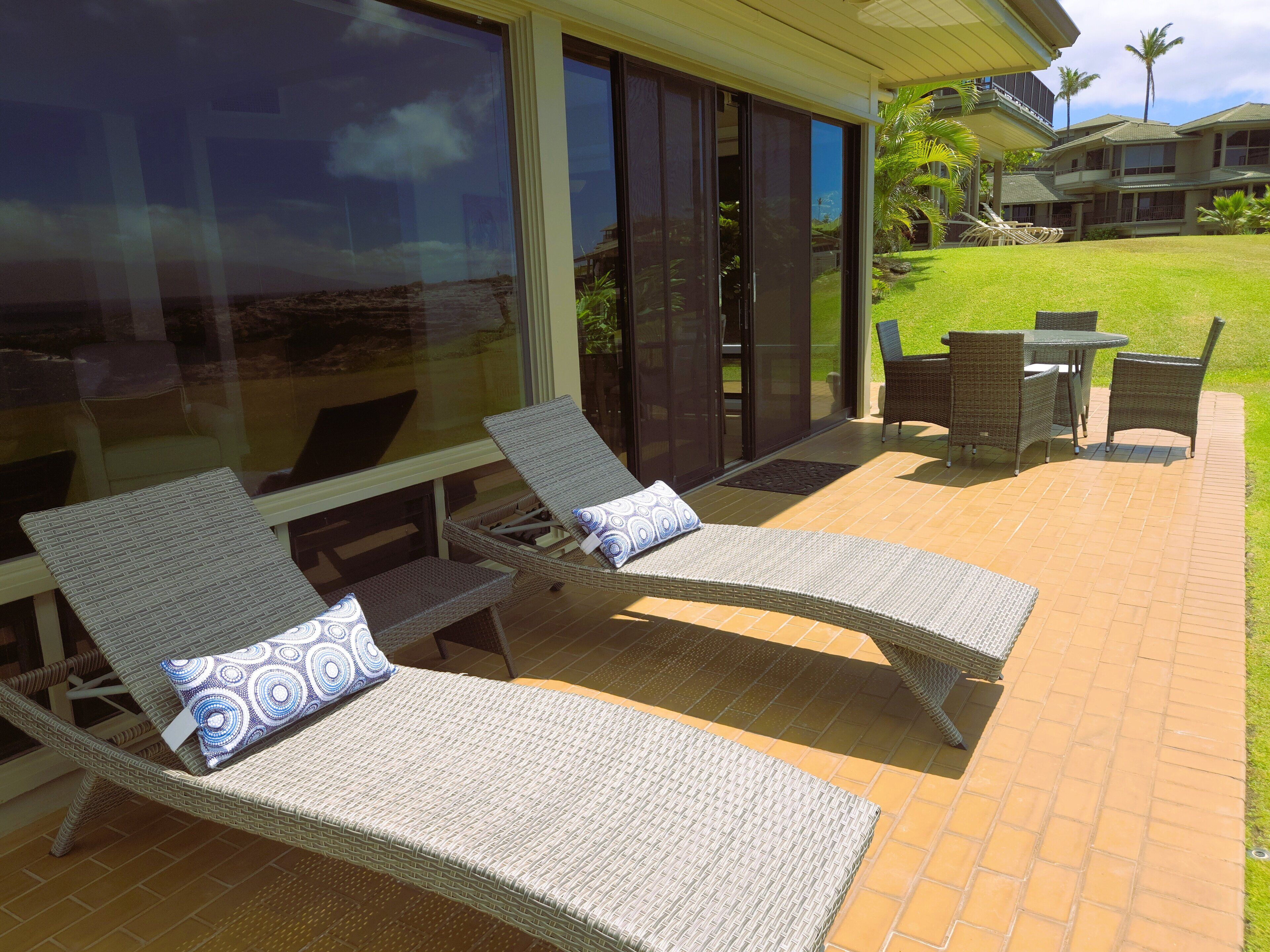 Eine Terrasse mit zwei Korstühlen, einem kleinen Tisch und einem Sessel.