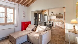 Un espacio de sala acogedor con un sofá, un armario rojo y una cocina al fondo.