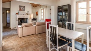 Una sala de estar acogedora con chimenea, una mesa de comedor con sillas y una estantería.