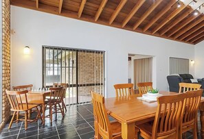 Un comedor con una mesa y sillas de madera, una pared de ladrillo y un ventanal grande.