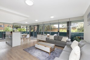 Ein modernes Wohnzimmer mit grauem Sofa, einem Couchtisch und einem Essbereich mit Tisch und Stühlen.
