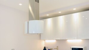 A modern kitchen with white cabinets, a central island, and a built-in microwave. - Brera Apartments Alla Scala (Milan)