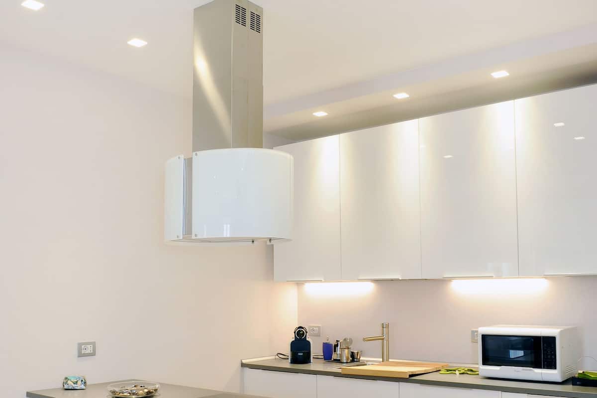 A modern kitchen with white cabinets, a central island, and a built-in microwave.