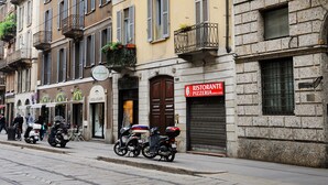 A street with buildings, a restaurant sign, and parked scooters. - Brera Apartments Alla Scala (Milan)