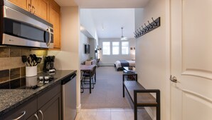 A modern kitchen with a built-in microwave, a coffee maker, and a dining area with a table and chairs.