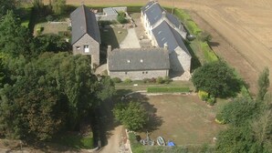 Vista aérea de una propiedad rural con dos casas de piedra, un campo grande y un pequeño jardín.
