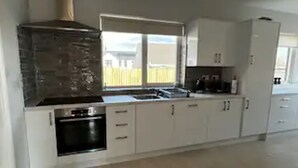 Eine moderne Küche mit weißen Schränken, einem eingebauten Backofen und einem großen Fenster für natürliches Licht.