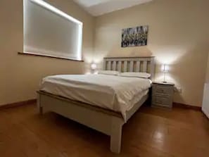 A bedroom with a bed, nightstand, and wall-mounted artwork.