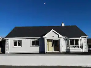 A two-story house with a dark roof, white exterior walls, and a front door.