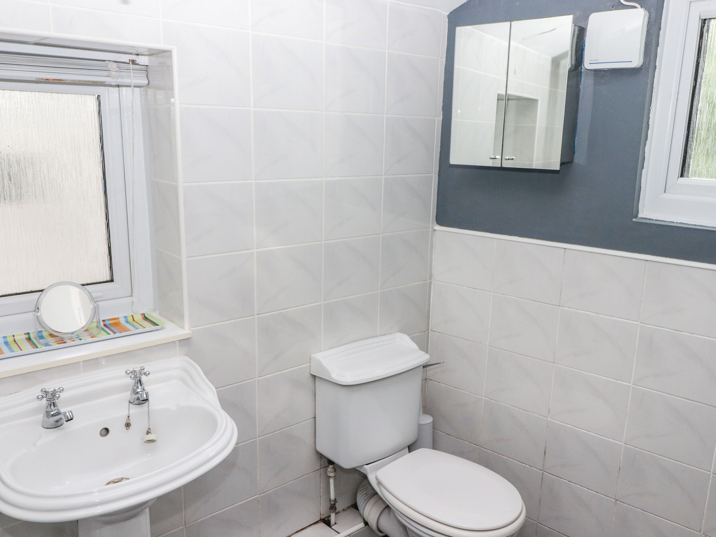 A bathroom with a white sink, a toilet, and a mirror above the sink.