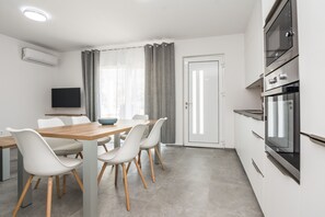 Une cuisine moderne avec un coin repas, un four encastré et un téléviseur à écran plat.