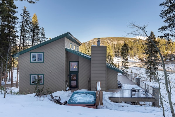 A two-story house with a deck, a hot tub, and a chimney. - 8 Crown Drive by Summit County Mountain Retreats (Breckenridge)