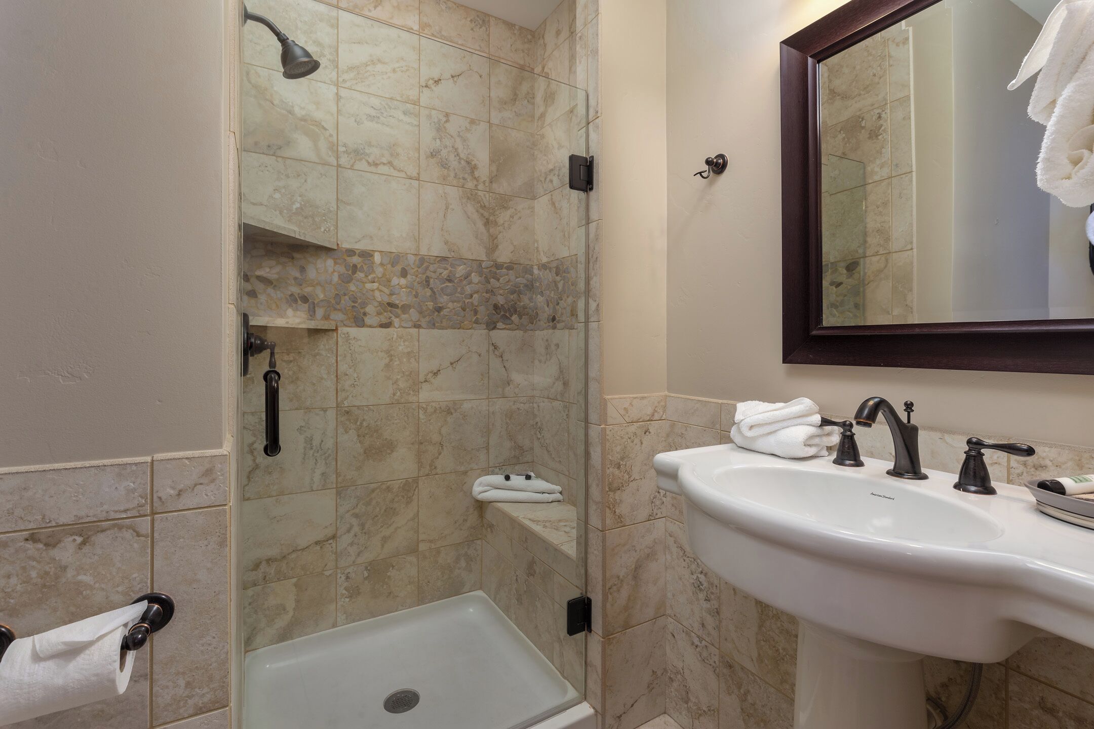 A bathroom with a shower, a sink, and a mirror.