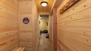 Un corridoio in legno con una panca, un cartello con la scritta 'Benvenuti, scarico qui' e una porta che dà su un'altra stanza.