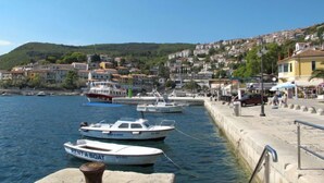 A coastal town with boats docked at the harbor, a stone quay, and buildings in the background. - Apartment Flores by Interhome (Rabac)