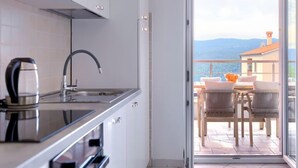 A modern kitchen with a kettle, a stove, and a sink. - Apartment Flores by Interhome (Rabac)