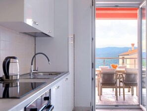 A modern kitchen with a kettle, a stove, and a sink. - Apartment Flores by Interhome (Rabac)