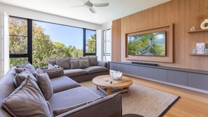 Ein modernes Wohnzimmer mit einem Ecksofa, einem runden Couchtisch und einem flachbildfernseher an der Wand.