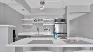 Een moderne keuken met witte aanrechtbladen, een roestvrijstalen koelkast en een magnetron.