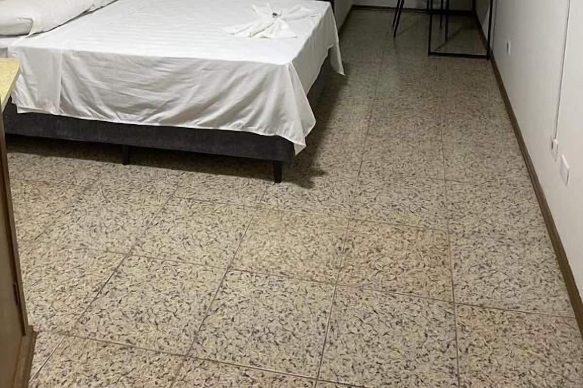 A small, clean room with a bed, a desk, and a chair.