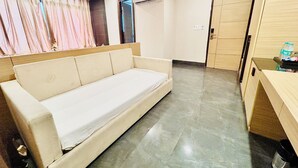 A room with a sofa, an air conditioning unit, a wooden door, and a tiled floor. - Hotel Aqua Vibes (Rishikesh)