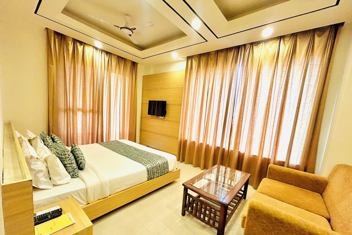 Una habitación de hotel con cama, sofá, mesa de centro y cortinas.