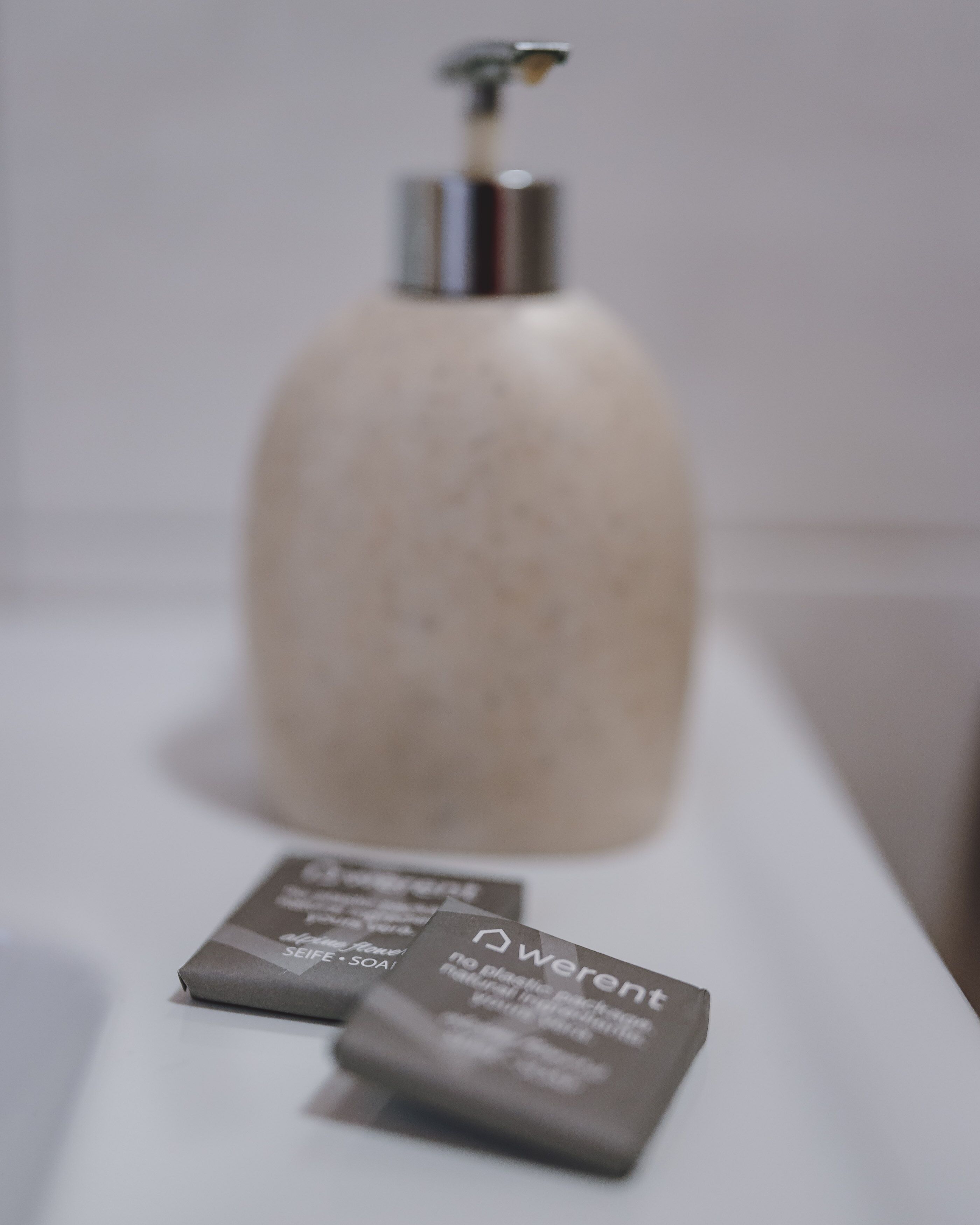 A bathroom with a large, round, beige dispenser and a small, rectangular, brown package on the counter.