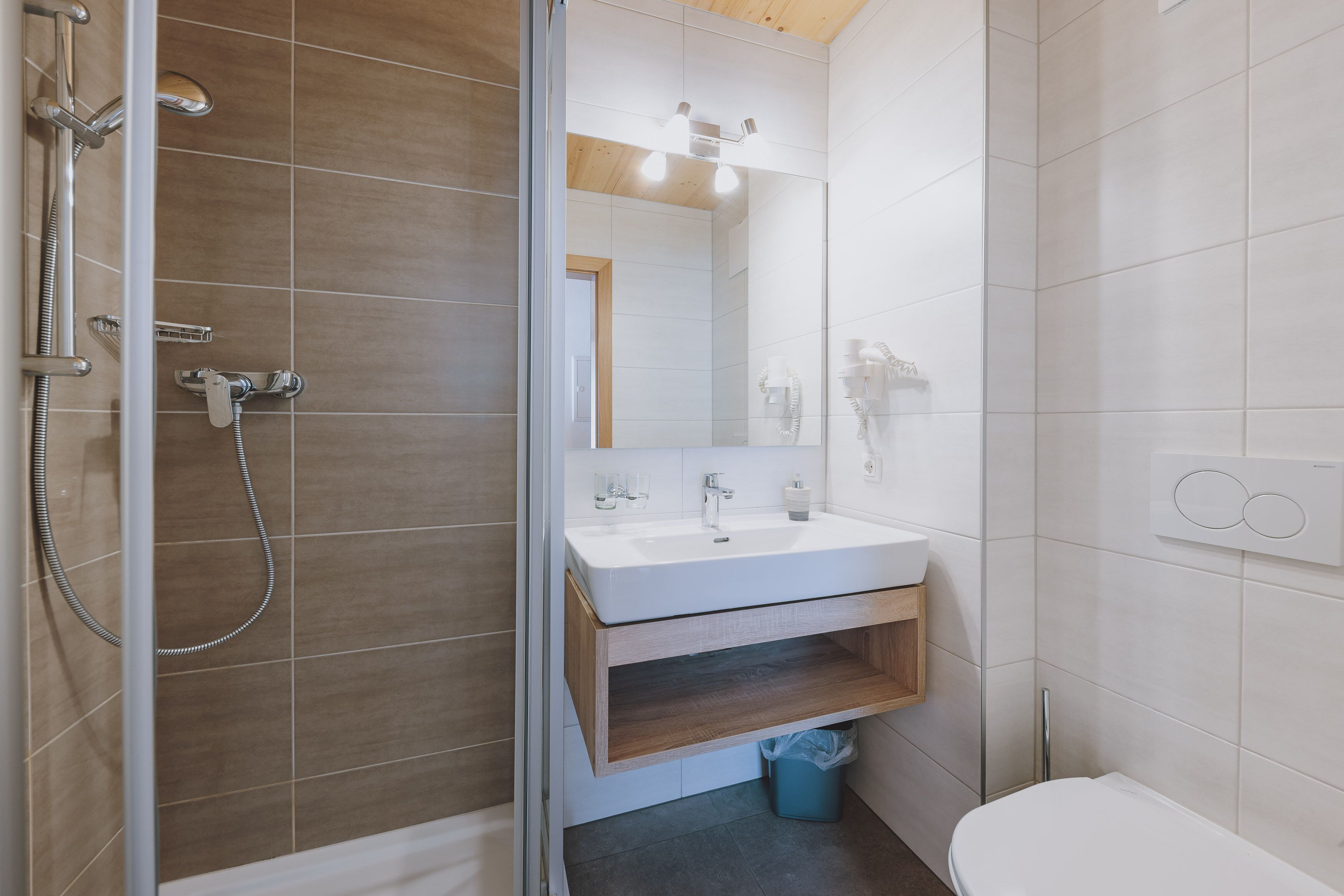 A modern bathroom with a shower, sink, and toilet.