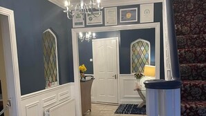 A hallway with a chandelier, a white door, and a patterned carpet. - Parkhouse Bed and Breakfast (Bunratty)