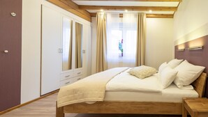 Un dormitorio con una cama de madera, una mesita de noche, un armario y una ventana con cortinas.