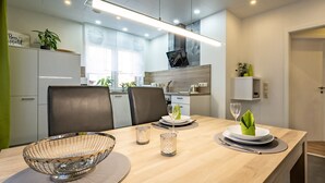 Una cocina moderna con zona de comedor, que cuenta con un ventanal grande, un televisor de pantalla plana y un diseño minimalista.