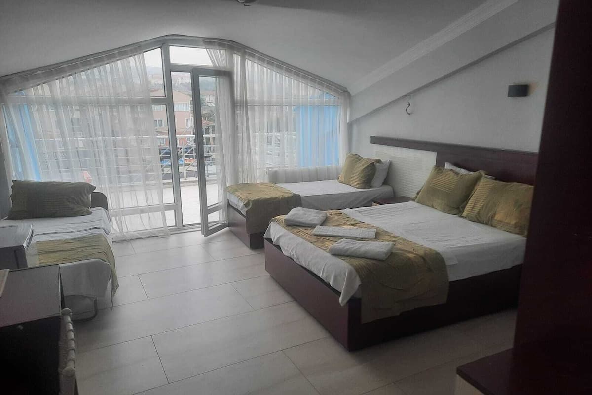 Habitación de hotel con dos camas, un escritorio y un ventanal grande con cortinas.
