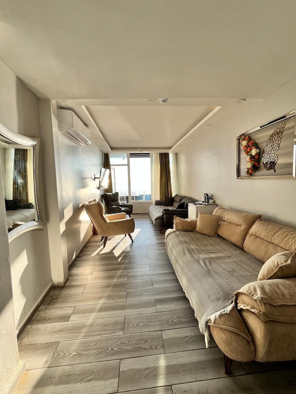 A modern living room with a sofa, armchair, and a TV. - Deniz Otel (Istanbul)