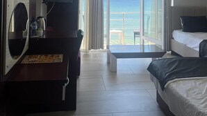 Habitación de hotel con cama, escritorio con televisor, vista al océano y aire acondicionado.