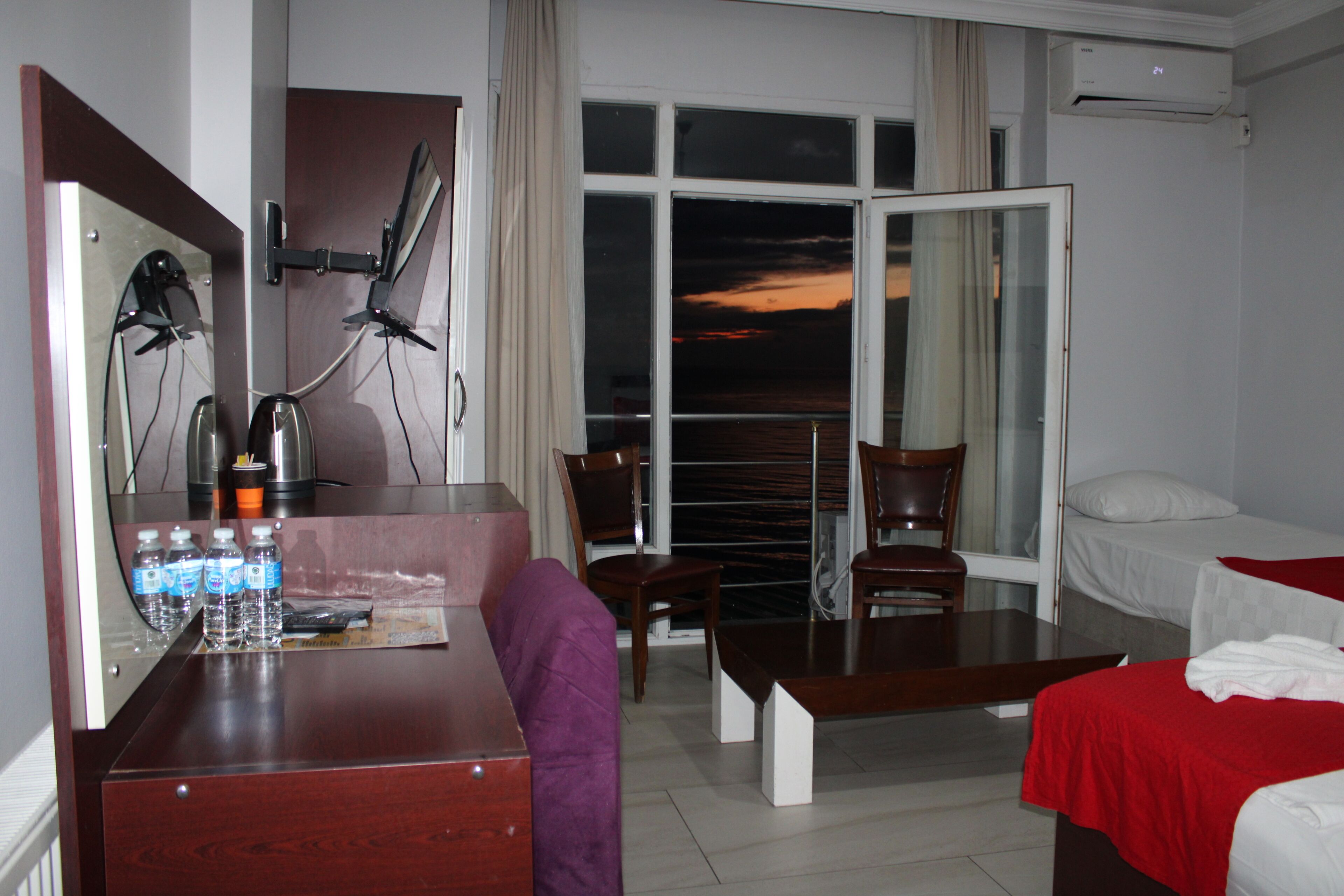 Habitación de hotel con escritorio, sillas, cama y ventana grande con vistas.