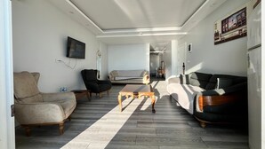 Una sala de estar moderna con sofá, sillón, mesa de centro y televisor de pantalla plana montado en la pared.