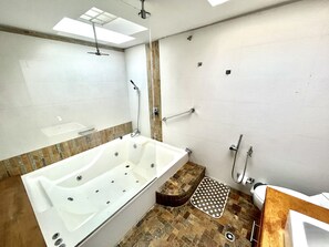 A modern bathroom with a large bathtub, a shower area, and a toilet.