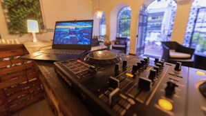 A DJ setup with a laptop and mixer, wooden crates, and a plant. - Ámbar Hostel  San Gil (San Gil)