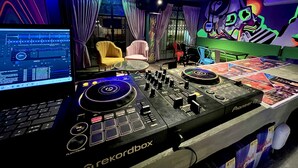 A DJ booth with Pioneer DJ equipment, a laptop displaying music software, and a colorful mural on the wall. - Ámbar Hostel  San Gil (San Gil)